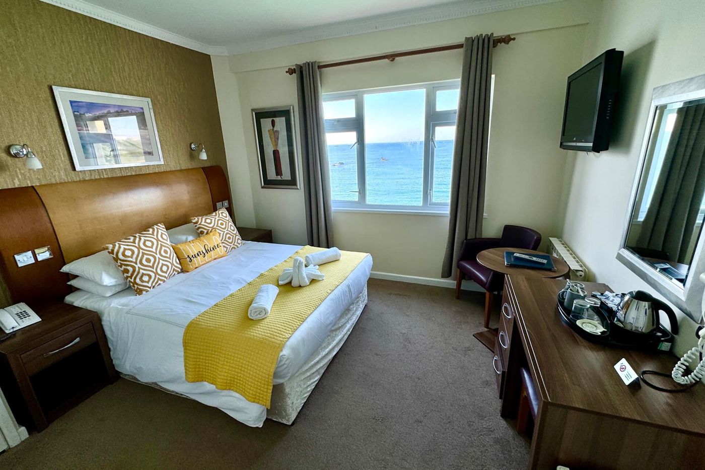A sea view bedroom at Marina Metro Hotel, St Helier, with tea and coffee facilities, television and a window onto the sea